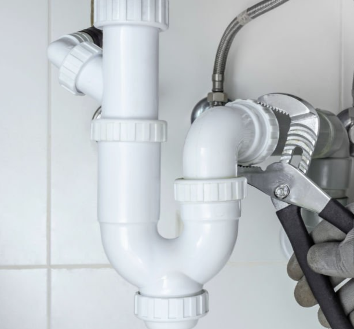 Plumber tightening a fitting beneath a sink
