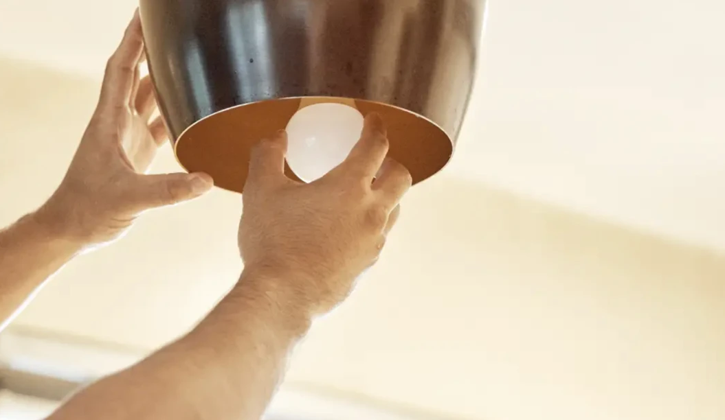 Technician replacing a ceiling light fitting